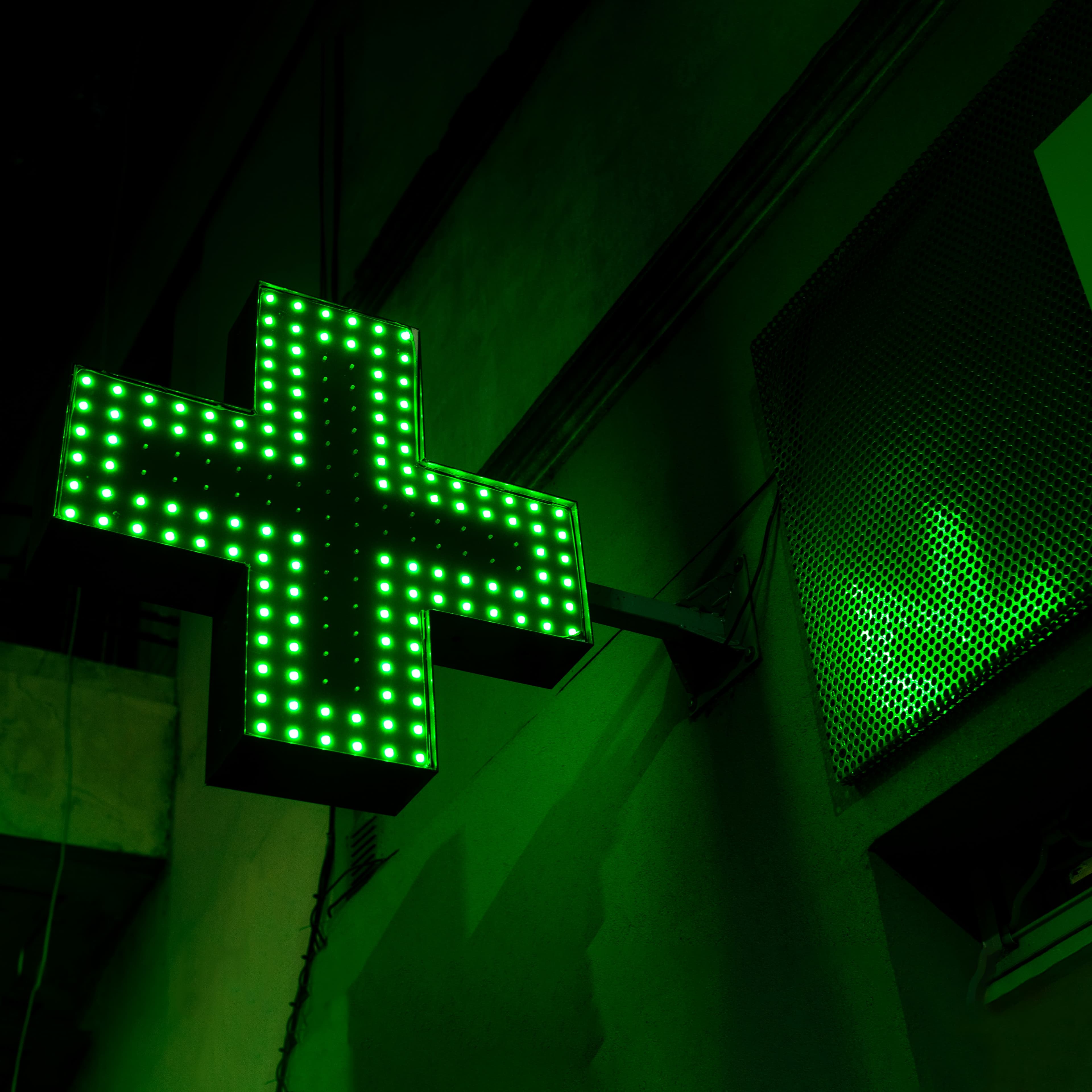 Insegna a croce verde a LED accesa sulla facciata, di sera